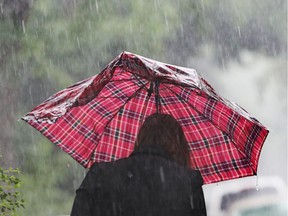 A woman walks in a heavy rain carrying an umbrella