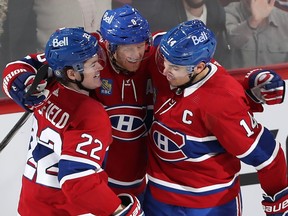 Canadiens defenceman Mike Mathson is flanked by COle Caufield, left, and Nick Suzuki in a group hug after a goal was scored at the Bell Centre.
