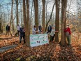 People gather in a wooded area around a homemade banner