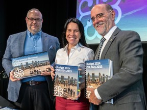 Montreal executive committee vice-chair Benoit Dorais, Mayor Valérie Plante and city director general Serge Lamontagne smile as they hold copies of the city's 2024 operating budget.