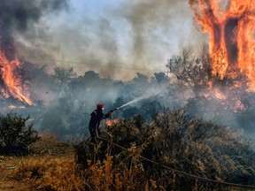A firefighter works on a wildfire at Panorama settlement near Agioi Theodori, some 70 kms west of Athens on July 18, 2023.