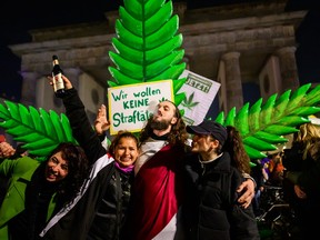 Cannabis smokers celebrate in front of a giant mock cannabis plant at a demonstration outside Berlin's Brandenburg Gate to mark the coming into force in Germany on April 1, 2024 of a law allowing adults to carry up to 25 grams of dried cannabis and grow up to three cannabis plants at home.