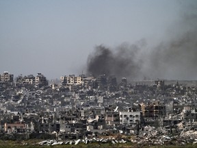 This picture taken from Israel's southern border with the Gaza Strip shows smoke billowing behind destroyed buildings due to Israeli strikes on the besieged Palestinian territory on April 2, 2024, amid the ongoing conflict between Israel and the militant group Hamas.