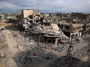 Palestinians walk past damaged buildings in Khan Yunis on April 8, 2024.