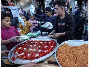 Palestinian vendors sell sweets at an open market in Rafah in the Gaza Strip on April 9, ahead of Eid al-Fitr, which marks the end of Ramadan. In times of war and unease, people must find ways to remember they are not alone, Gerald Wiviott writes. (Photo by MOHAMMED ABED / AFP)