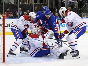 Canadiens hockey players surround a lone Rangers player in front of the net
