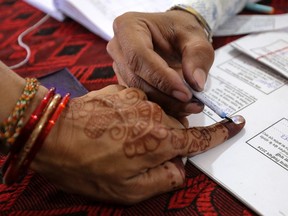 A polling officer marks the finger of a voter before casting her vote during first phase of parliamentary elections at a polling booth in Chhindwara on April 19, 2024.