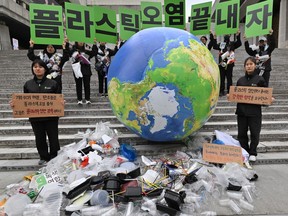 Environmental activists hold up placards reading "Let's end plastic pollution!" as they display plastic waste with an Earth balloon during a campaign event to mark the international Earth Day in Seoul on April 22, 2024.