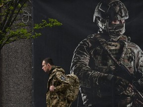 A Ukrainian serviceman walks past a recruiting poster in Kyiv on April 23, 2024, amid the Russian invasion of Ukraine.