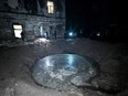 Law enforcement officers inspect a crater next to a building following a missile attack in Kharkiv early on April 27, 2024.
