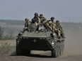 Ukrainian servicemen ride on an armored personnel carrier (APC) in a field near Chasiv Yar, Donetsk region, on April 27, 2024, amid the Russian invasion of Ukraine.