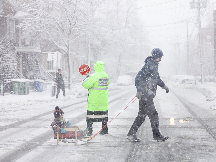 Winter is not going out with a whimper as a crossing guard holds traffic while a father and child cross at LaSalle Blvd. and Wellington St. in Verdun.
