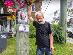 A sombre man leans on a pole on which a photo of his deceased daughter is taped. Flowers are placed above the photo.