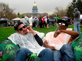 Kevin Barron, left, and Lasean Moore of Raleigh, North Carolina, share a joint during the Denver 420 Rally at Civic Center Park in Denver, Colorado on April 20, 2017.