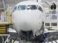 A front view of an airplane, with a worker resting on an elevated platform next to the craft.