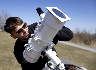 A man checks his telescope ahead of the solar eclipse.