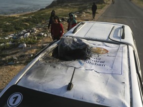 Palestinians inspect a vehicle with the logo of the World Central Kitchen wrecked by an Israeli airstrike in Deir al Balah, Gaza Strip, Tuesday, April 2, 2024.