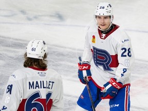 Rocket's Lias Andersson is seen in Laval's white jersey speaking to teammate Philippe Maillet, who has his back to the camera, during an AHL hockey game in Laval last November.
