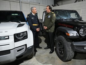 Deputy Commissioner Marty Kearns of the Ontario Provincial Police, left, and Deputy Chief Benoit Dube of the Sûreté du Québec, talk near two recovered stolen vehicles in Montreal on April 3, 2024. The OPP and Canada Border Services Agency seized 598 stolen cars destined for export at the Port of Montreal. THE CANADIAN PRESS/Graham Hughes