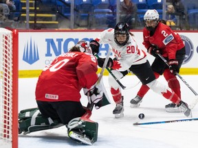 A hockey player for Canada drives to the net against Switzerland at the IIHF Women's World Hockey Championship