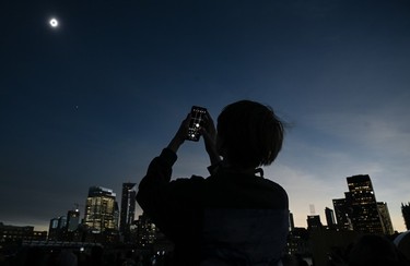 A person takes a photograph of the sun during totality as the moon passes between it and the earth resulting in a total solar eclipse, in Montreal, Monday, April 8, 2024.