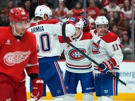 Three Canadiens celebrate on the ice while a Red Wings player looks unhappy