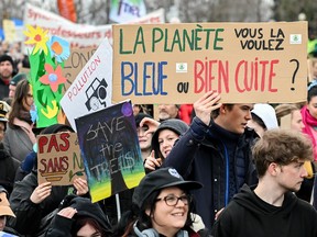 People, one of whom holds up a sign asking "Do you want the planet blue or well-done," march in Montreal on Earth Day