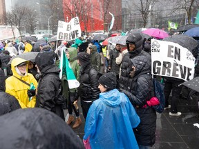 People hold picket signs outside in the rain