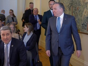François Legault walks past seated people in suits