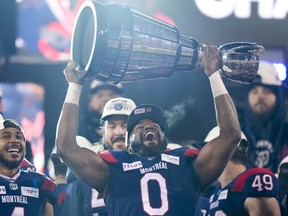 Alouettes defensive-end Shawn Lemon hoists the Grey Cup over his head in sheer joy.