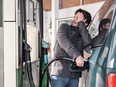 Young man refueling his vehicle while looking worried at the high gas prices.