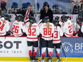 Canada head coach Troy Ryan, second left, gives directions to players with assistant coaches from left to right, Kori Cheverie, Caroline Ouellette and Courtney Kessel during their game against Switzerland at the IIHF Women's World Hockey Championship in Utica, N.Y., Friday, April 5, 2024.