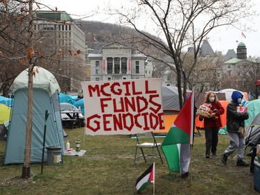 A sign that reads "McGill funds genocide" sits among tents in a campus encampment