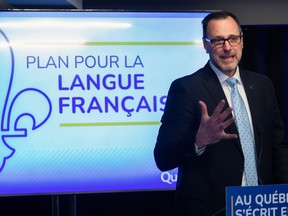 Quebec French Language Minister Jean-François Roberge speaks at a lectern in front of a screen reading Plan Pour La Langue Française.
