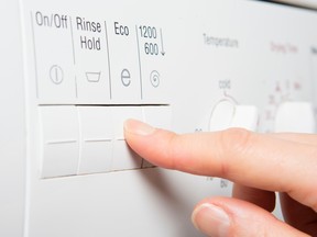 Finger pressing buttons on washing machine
