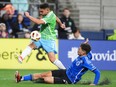 Soccer player leaps over another to control the ball