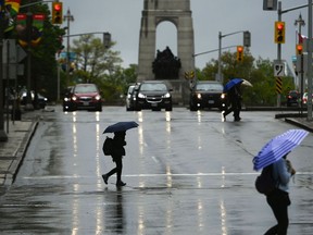 People cross Elgin St. as rain falls in Ottawa on Tuesday, May 17, 2022.