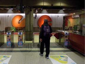 A view of the back of a balding man wearing knapsack approaching the pay machines to enter Villa-Maria métro station.
