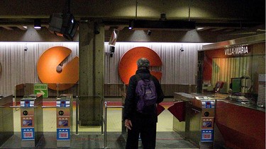 A view of the back of a balding man wearing knapsack approaching the pay machines to enter Villa-Maria métro station.