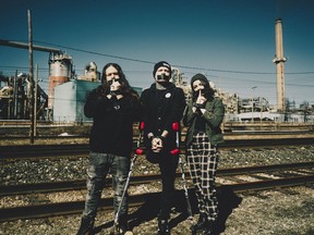 Members of the metal band Guhn Twei stand in front of the Horne copper smelter in Rouyn-Noranda, Que., in an undated handout photo. A music festival in western Quebec has been cancelled after lead singer Simon Turcotte, centre, accused organizers of rescinding an invitation to perform because of its criticism of an arsenic-emitting copper smelter.