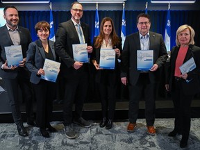 Quebec ministers Mathieu Lacombe, Christine Fréchette, Jean-François Roberge, Pascale Déry, Bernard Drainville and Martine Biron smile for the cameras while holding copies of the provincial government's action plan for the status of French.