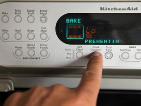 A person hits a preset button on an oven.