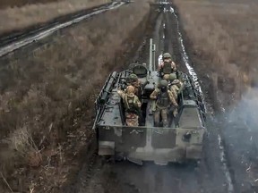 In this photo taken from video released by Russian Defense Ministry Press Service on Saturday, April 13, 2024, Russian Army soldiers ride their armoured vehicle to take positions and fire toward Ukrainian positions at an undisclosed location in Ukraine.