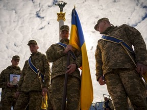 Ukrainian servicemen walk ahead of the coffin of their fallen fellow Vadym Popelniuk, born in 1991, carrying his photograph during a religious service in Independence Square in Kyiv, Ukraine, Friday, April 5, 2024.