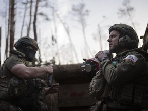 A Ukrainian serviceman from the Azov brigade known by call sign Chaos, right, carries mortar shell
