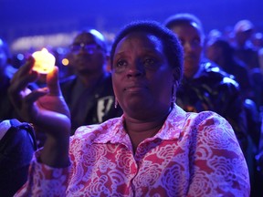 A woman sitting in the stands, holds a candle as part of a candlelit vigil during the memorial service held at Amahoro stadium in the capital Kigali, Rwanda, Sunday, April 7, 2024.