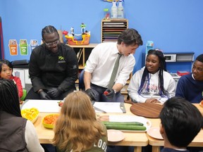 Prime Minister Justin Trudeau talks to 10-year-old Chakai as he cuts fruit next to chef Jason Simpson while preparing food for a lunch program at the Boys and Girls Club East Scarborough, in Toronto, Monday, April 1, 2024.