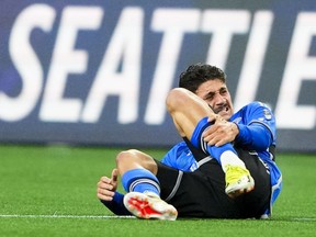CF Montréal striker Matias Coccaro is seen lying down while holding his left leg and grimacing in pain.