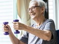 An older woman lifts hand weights