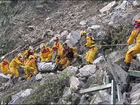 In this photo taken Thursday, April 4, 2024 and released by Pingtung Fire Department, firefighters remove a body from the Taroko National Park a day after a powerful earthquake struck, in the Hualien county, eastern Taiwan.